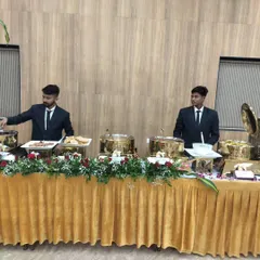 My professional staff, dressed in smart uniforms, attending to a buffet line with elegant golden chafing dishes at a corporate event.