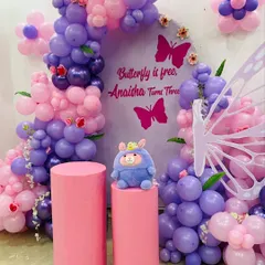 "Butterfly is free, Anaisha turns three!" This whimsical butterfly theme features a beautiful balloon arch in shades of purple and pink, a personalized backdrop, large butterfly wings, and matching pink pedestals.