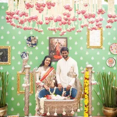 A portrait of the new parents with their baby in an ornate silver cradle, set against a custom-designed pastel green backdrop.