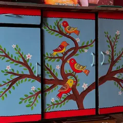 I gave this old cupboard a complete makeover with a vibrant, hand-painted mural. The design features colorful birds perched on a flowering tree, turning a functional piece of furniture into a statement art piece for the home.