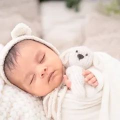 Dressed in a cozy bear bonnet and holding a tiny knitted friend, this baby is the picture of innocence. I use soft, neutral-colored props for a classic look.