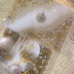 An elegant gift set in white and gold, perfect for Eid or any special occasion. This set includes a resin Quran box, a matching bookmark, and other accessories, all embellished with crystals and pearls for a luxurious finish.