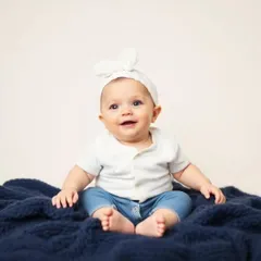 An indoor studio-style portrait of a smiling baby against a clean, simple background. We provide controlled lighting and backdrops for classic baby photos.