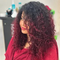 Curly hair on fire. This client wanted a bold change, so we created this stunning red ombre effect that perfectly complements her natural curl pattern.