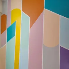 A close-up of a colorful geometric wall design, using a playful palette of pastel and bright colors like yellow, orange, and teal for a vibrant effect.