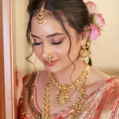 A close-up of this subtle and elegant bridal makeup. The focus is on the soft, blended eyeshadow and the radiant skin, complemented by fresh flowers in her hair.