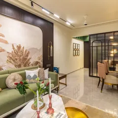 An open-plan living and dining area that feels both cohesive and distinct. The statement wallpaper acts as an anchor for the living space, while the green sofa adds a refreshing touch of color that connects with the natural theme.