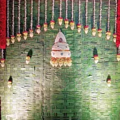 This is a full view of one of our Varamahalakshmi pooja backdrops. The design includes a woven coconut leaf mat, a red flower border, and hanging floral elements, including a traditional cone-shaped flower arrangement at the center.