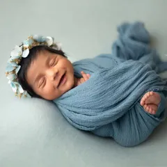 The sweetest smile from this beautifully swaddled baby girl. The simple blue wrap and delicate floral crown highlight her happy dreams.
