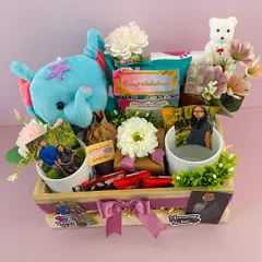 A full view of the parents-to-be hamper, decorated with a cute elephant plushie and flowers. It's a perfect gift for a baby shower.