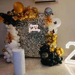 A chic black, white, and gold decoration against a silver sequin wall. This setup includes a 'Happy Birthday' neon sign and a light-up number '2', creating a sophisticated and modern look.