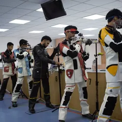 A different perspective of the firing line during a simulated final. Shooters learn to block out distractions and focus solely on their own performance, a key skill for any competitive athlete.
