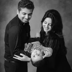 A playful and heartwarming black and white family portrait. Holding the baby upside down brings out genuine smiles and creates a dynamic, memorable shot.