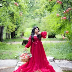 A fairytale outdoor portrait. This mama-to-be is in a beautiful apple orchard, her red gown creating a storybook scene.