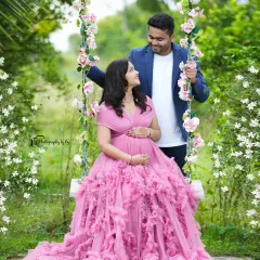 A candid moment of joy on our floral swing. The expecting mother is wearing a magnificent ruffled pink gown, creating a fairytale-like scene in our private garden.