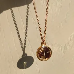 A single, precious rose preserved in a simple, round rose gold pendant. The sunlight catches the delicate details of the petals, making it a truly special piece.