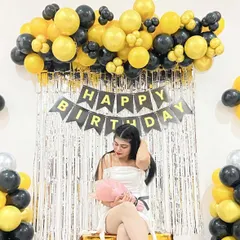 A guest poses in front of the yellow and black birthday decoration, showing how it creates a great photo opportunity.