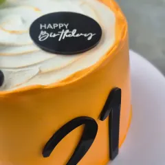 A detail shot of the 21st birthday cake, showing the smooth whipped cream finish and the "Happy Birthday" topper.