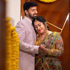 A warm, loving portrait of a couple during their housewarming ceremony, surrounded by traditional marigold flower decorations.
