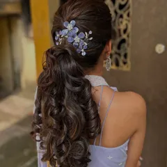 Hairstyling is just as important as makeup. Here, I’ve created a voluminous, textured ponytail with soft curls, accented with custom floral pieces that perfectly match the client's lavender outfit, ideal for a chic reception look.