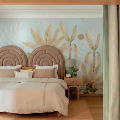 The kids' suite in Summer Haus features a beautiful, hand-painted wallpaper that creates a whimsical, tropical atmosphere. The custom-designed headboards and soft, neutral bedding provide a calm counterpoint to the vibrant walls.