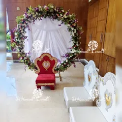 An elegant and traditional setup for an Annaprashan puja ceremony. A large ring decorated with real flowers provides a beautiful backdrop for the baby's special chair, creating a sacred and memorable space.