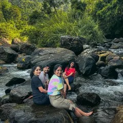 A group of friends sits on rocks in a private water stream in Munnar. I find these exclusive, offbeat spots for you to enjoy nature without the crowds.