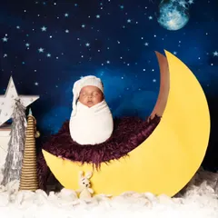 A slightly different angle of our moon prop, showing the sleeping baby nestled comfortably on a soft purple blanket. We adjust lighting and props to create a variety of shots within one theme.