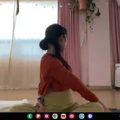 Through the screen, I guide a student in a seated twist. These online sessions help you build body awareness, making it easier to correct your own posture throughout the day.
