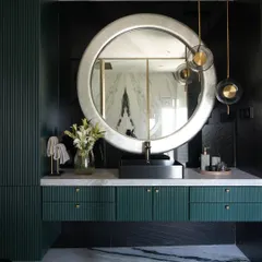 This master bathroom is a study in bold luxury. We paired deep green fluted cabinetry with dramatic black and white marble flooring. The large, silver-leafed circular mirror and pendant lights add a layer of glamour, creating a truly sophisticated sanctuary.