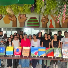 A group photo from a "Paint & Express" workshop, with everyone displaying their diverse and colorful canvases.