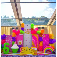 This vibrant photo backdrop for a 6th birthday is a carnival of colour. It features multiple panels with different patterns, balloon garlands, and fun 3D props like a giant cupcake, a rainbow, and the number '6'.