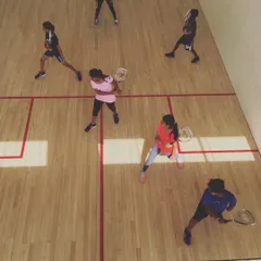 Players hold a lunge position, preparing their racquets for the next shot in a group drill. This exercise builds muscle memory for correct positioning and readiness during a rally.