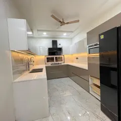 This U-shaped kitchen features a glossy, dual-tone design with white upper cabinets and beige lower cabinets. The marble-patterned flooring and quartz countertop create a bright and luxurious cooking environment.