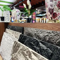 A display of our PU stone panel samples in various colors, from light grey to dark charcoal. You can see the realistic rock texture up close.