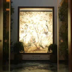 We blend art with nature to create serene focal points. This beautifully illuminated wall mural, featuring peacocks and foliage, is flanked by plants to create a captivating and peaceful entryway.