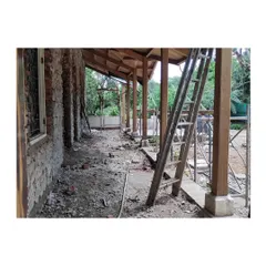 The veranda during the early stages of reconstruction. Here you can see the new wooden support pillars and the exposed load-bearing stone wall before the final finishes are applied, showing the skeleton of the restoration.