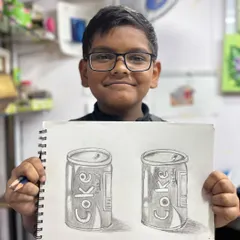 Fantastic progress after just six sessions. This 9 year old student proudly shows his pencil shading study of Coke cans, where he learned to create form and texture.