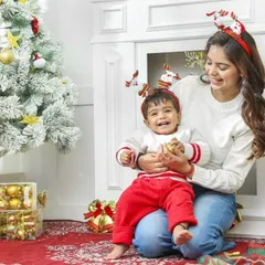 Christmas magic is in the air. This heartwarming photo captures a mother and son sharing a joyful moment by the Christmas tree in our festive studio.