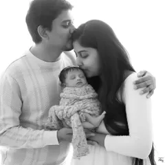 A classic high-key black and white portrait. The bright, airy feel brings all the focus to the family's gentle kisses and the sleeping baby they adore.