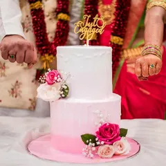 A close-up of the "Just Engaged" cake topper and the couple's hands with their new rings. It's all about celebrating the beginning of your new journey.