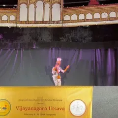 A single puppet commands the stage against the backdrop of the Gagan Mahal, representing the grandeur of the Vijayanagara empire. The intricate stage design is as much a character in the story as the puppets themselves.