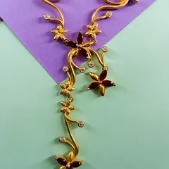 A detailed shot of the gold-plated floral necklace, highlighting the intricate craftsmanship of the red stone flowers and sparkling zirconia accents.