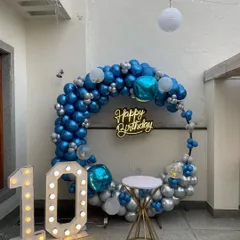 A stylish 10th birthday setup on a home terrace, featuring a blue and silver balloon ring and a light-up marquee number.