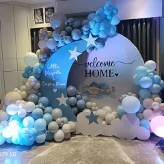 A "Welcome Home Little Miracle & Super Mom" setup with a celestial moon and stars theme. The blue, white, and beige balloons create a calming and dreamy look, celebrating both the new baby and the new mother.