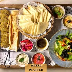 A closer look at another one of my Mezze Platters. This one includes crispy falafel, lavash sticks, a basket of pita bread, fresh salad, and a variety of dips, all arranged on a tray with delicate lace.