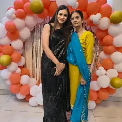 A client celebrating with her mother, looking stunning in a classic black sequin saree. This timeless piece is perfect for any celebration.