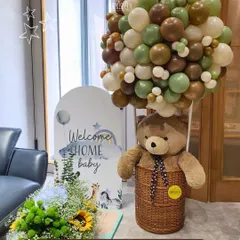 A bear-y warm welcome for the littlest love! This hot air balloon basket with a teddy bear and an organic balloon arrangement in earthy tones is a perfect, adorable setup for a baby's homecoming.