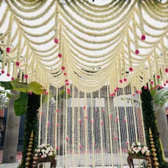 A breathtaking curtain of fresh jasmine flowers (malli poo) creates a fragrant and visually stunning backdrop. This traditional element, accented with pink roses, is perfect for creating an atmosphere of natural elegance.