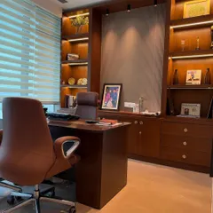 We designed this executive office to be both productive and aesthetically pleasing. The custom-built wooden shelving unit features integrated backlighting to highlight awards and decor, while the ergonomic leather chair and spacious desk provide ultimate comfort. The combination of rich wood tones and soft, layered lighting creates a powerful yet sophisticated workspace.